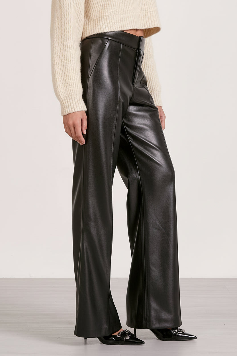Person wearing black leather pants with a plain background