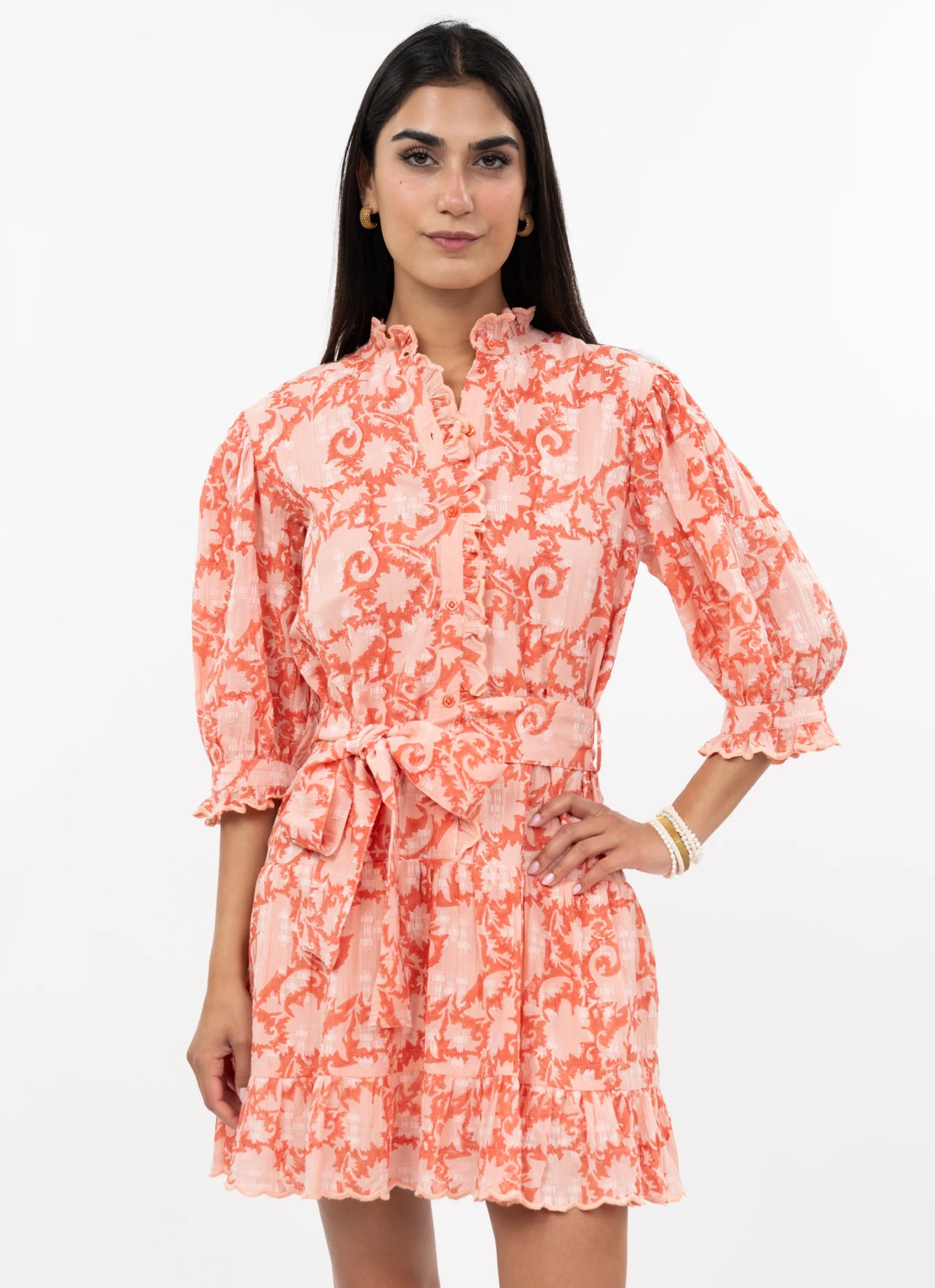 Woman wearing a coral floral dress on a white background
