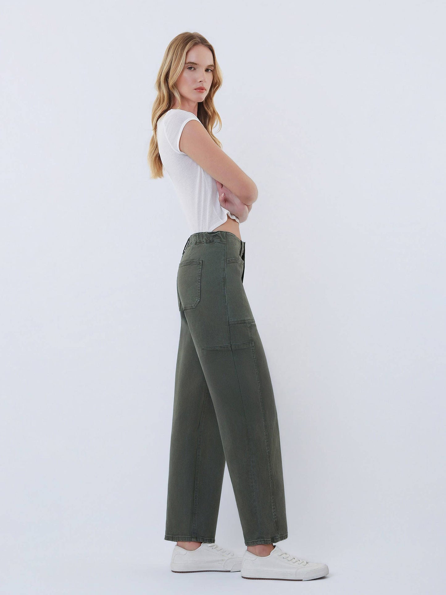Woman wearing green cargo pants and a white top on a white background