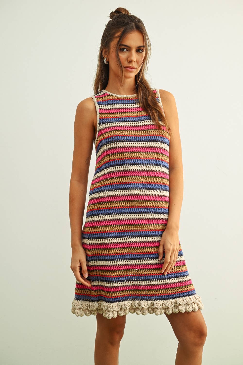 Woman wearing a colorful striped dress against a plain background