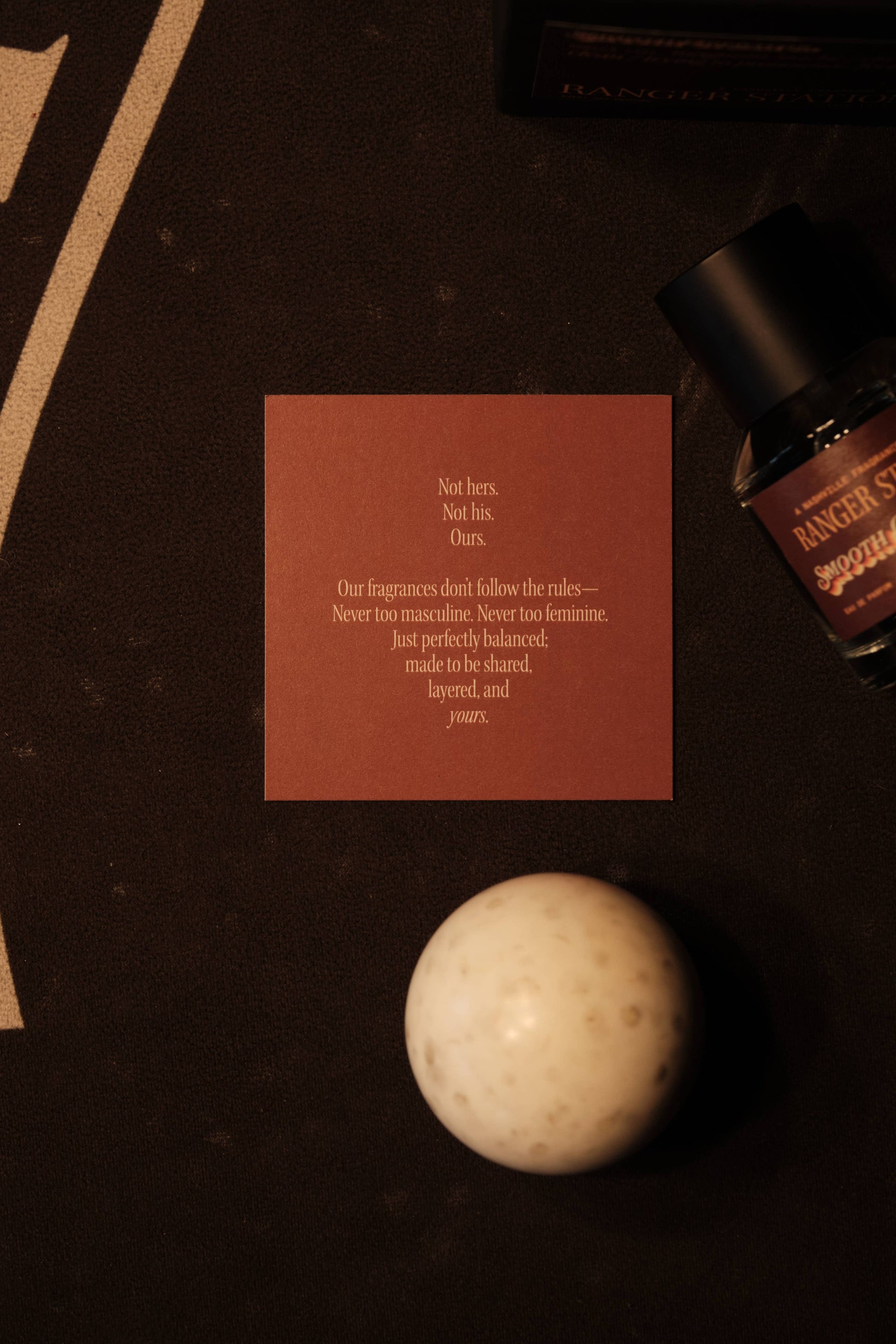 Cosmetic product with a red card and spherical object on a dark surface