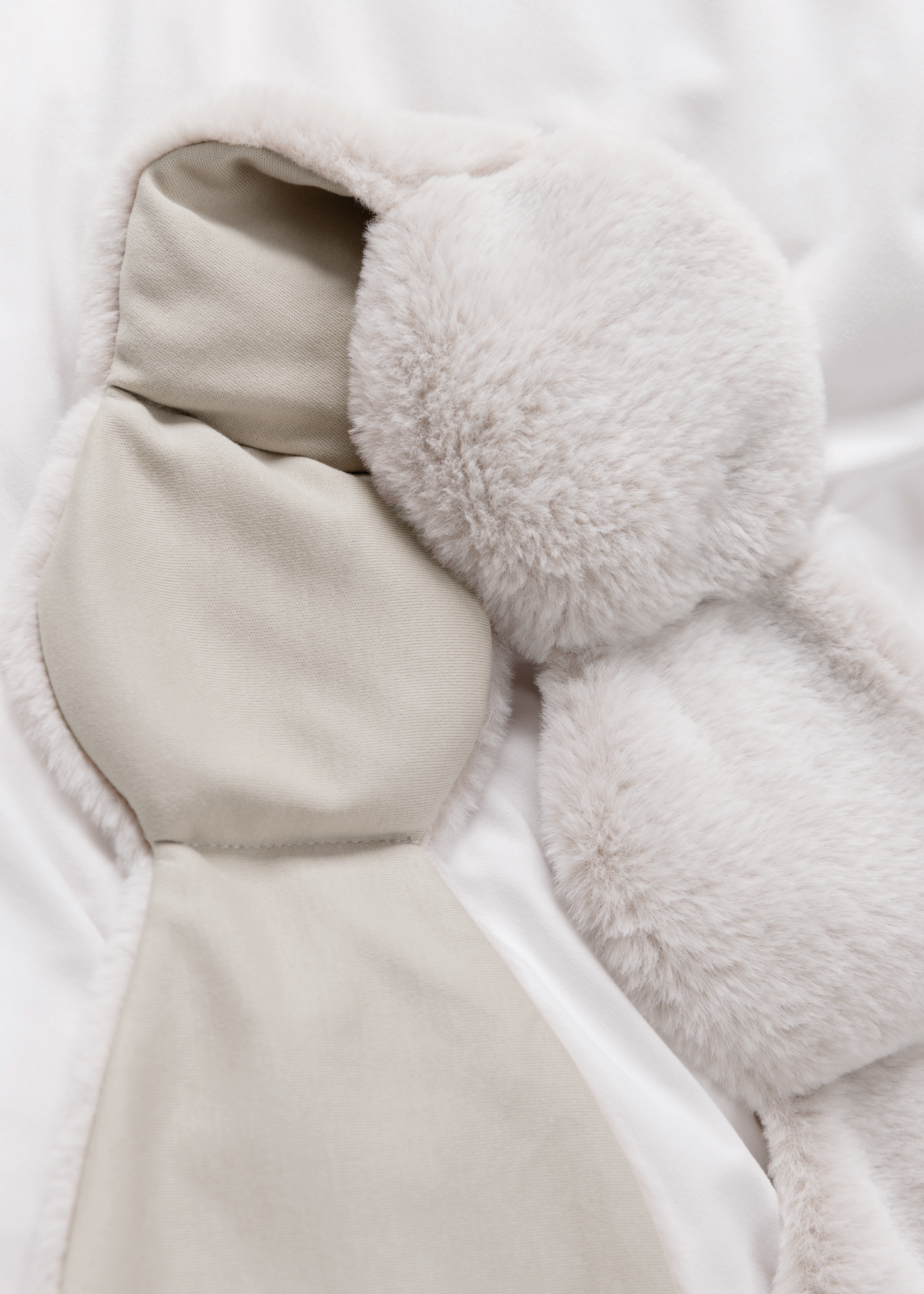 Close-up of a plush toy with bunny ears and a tail on a white background