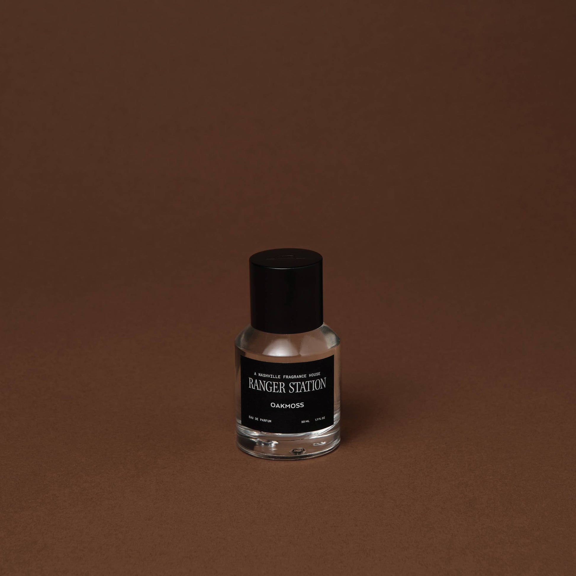 Perfume bottle with black cap and label on a brown background. Label says: Ranger Station Oakmoss