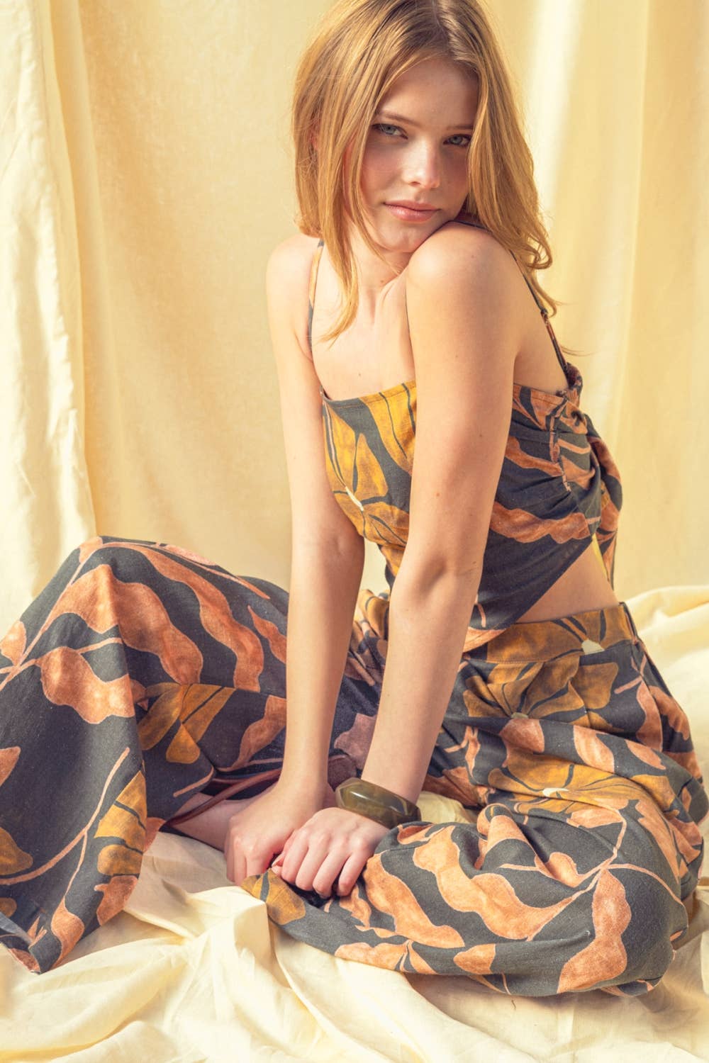 Woman wearing a patterned dress sitting on a light-colored fabric background