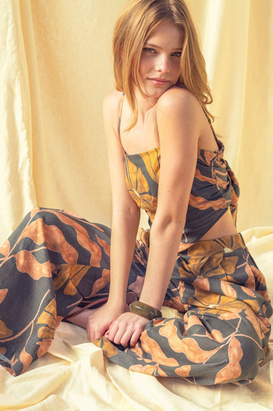 Woman wearing a patterned dress sitting on a light-colored fabric background