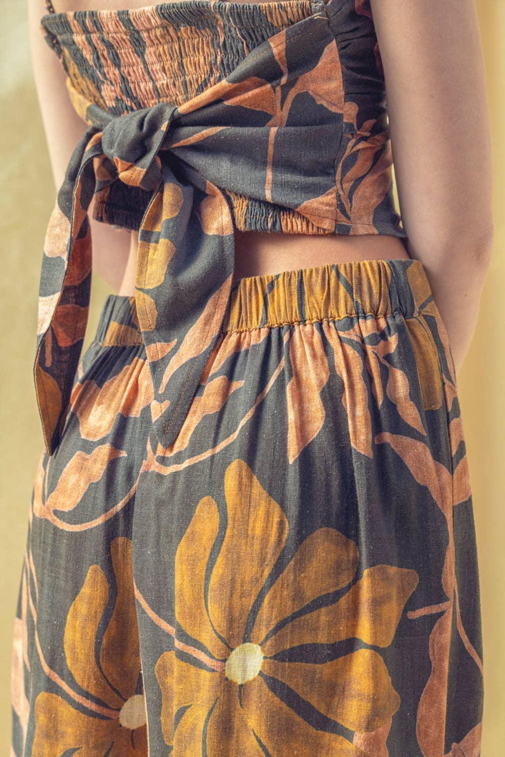 Person wearing a floral two-piece outfit with a yellow background