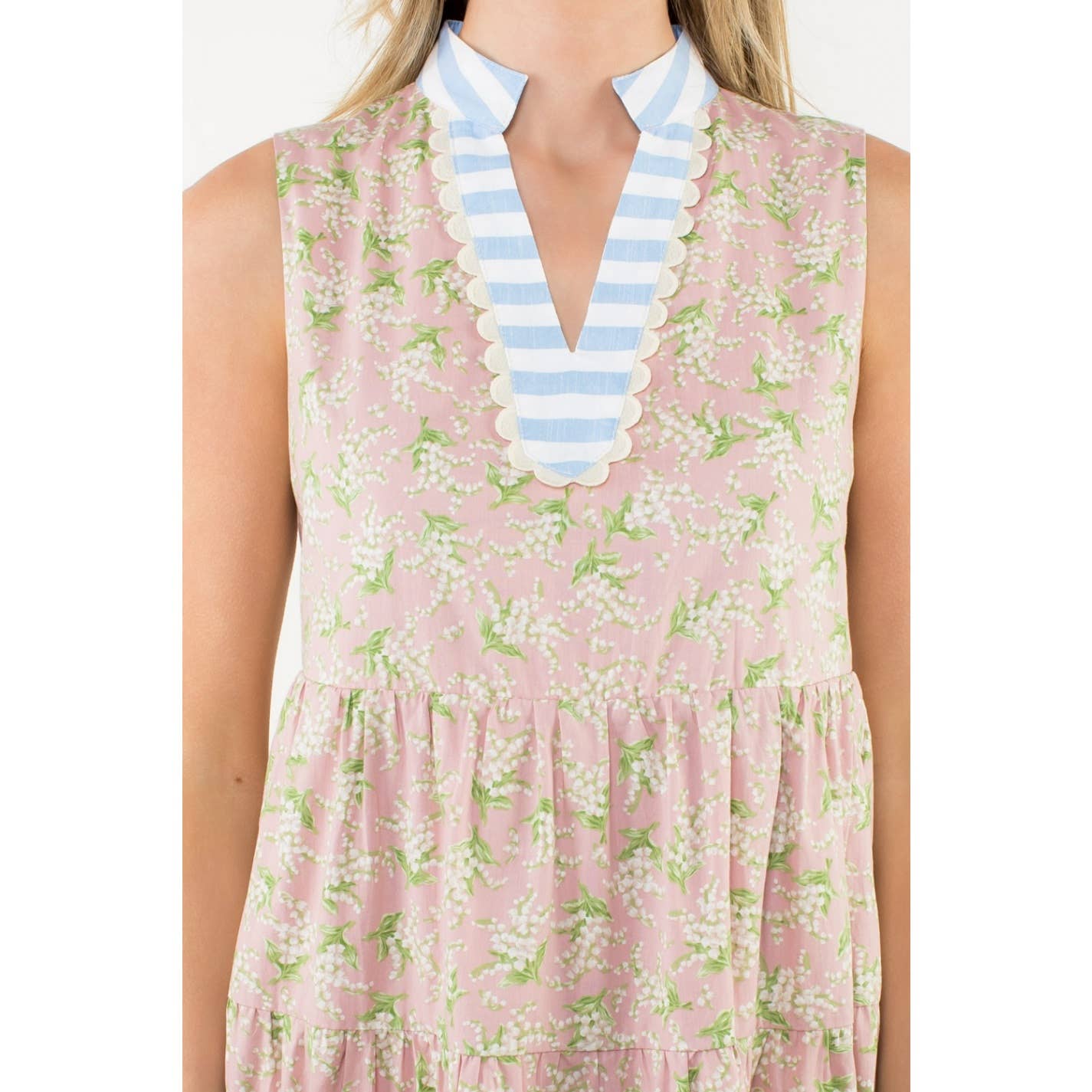 Woman wearing a pink floral dress with a blue and white striped collar on a white background