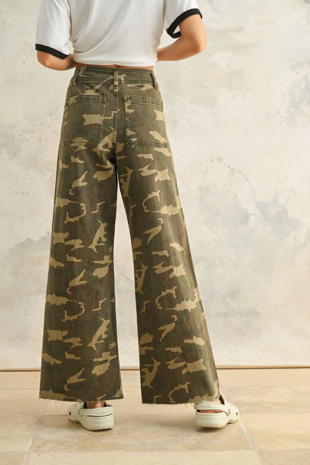 Person wearing camouflage wide-leg pants against a neutral background