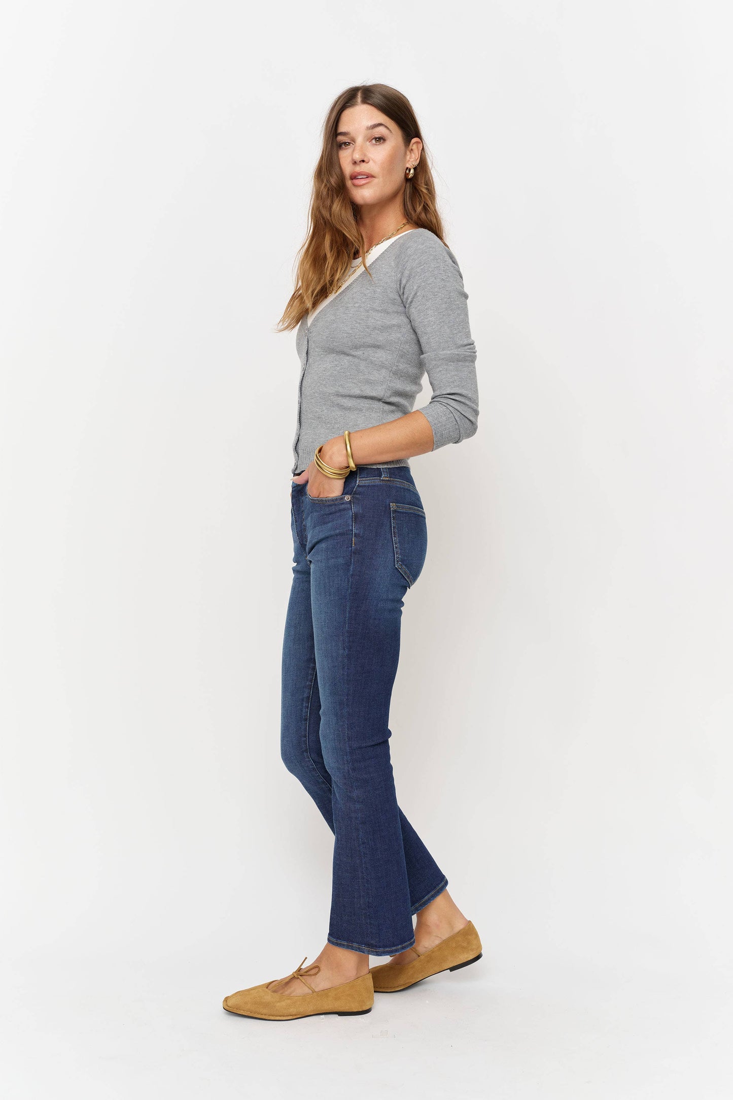Woman wearing a gray sweater and blue jeans on a white background