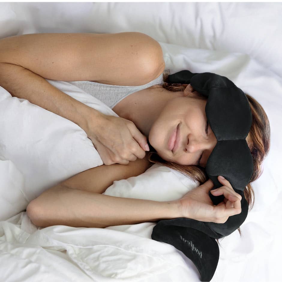 Person lying in bed wearing a black sleep mask.