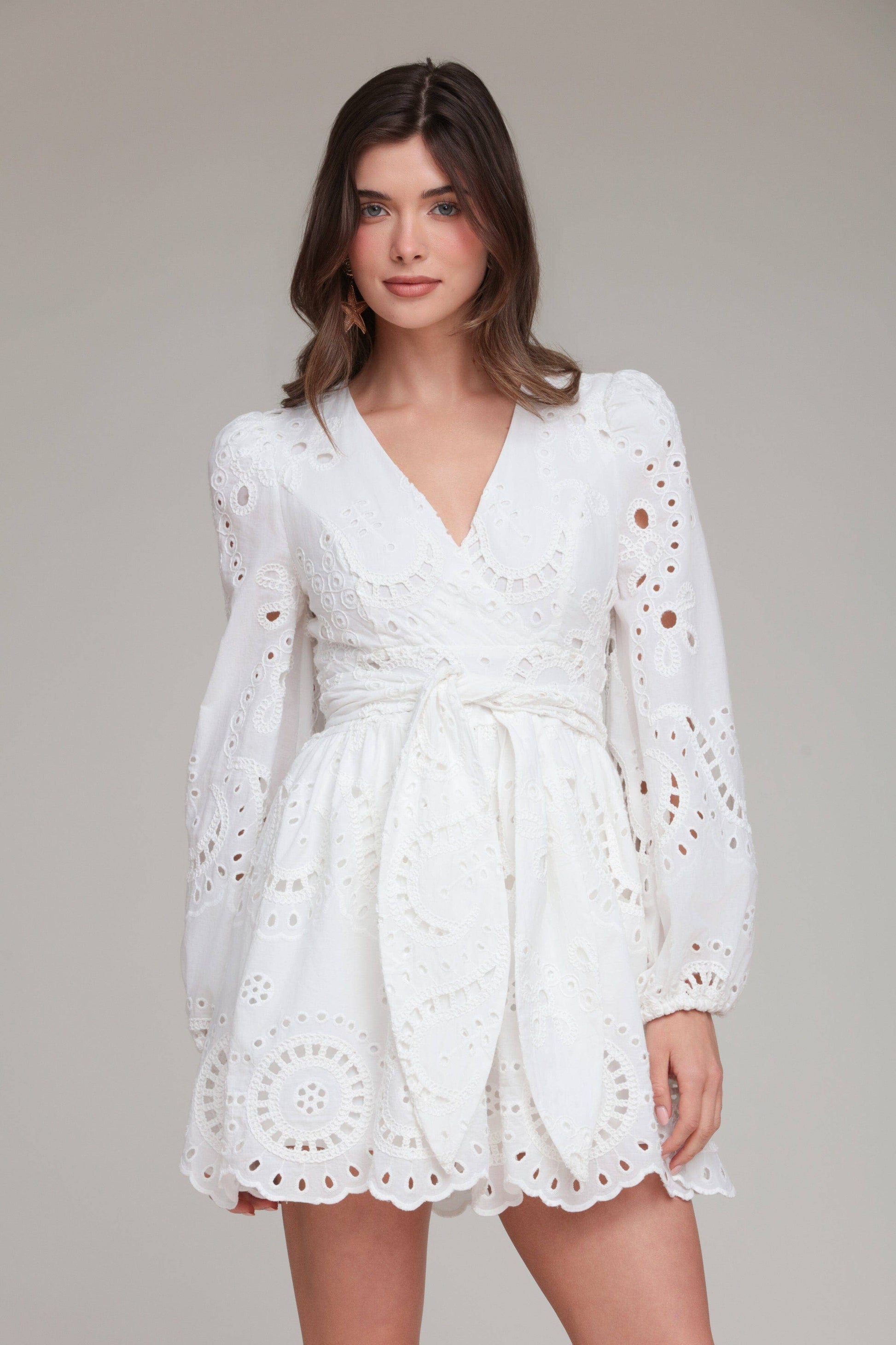 Woman wearing a white lace dress against a plain background