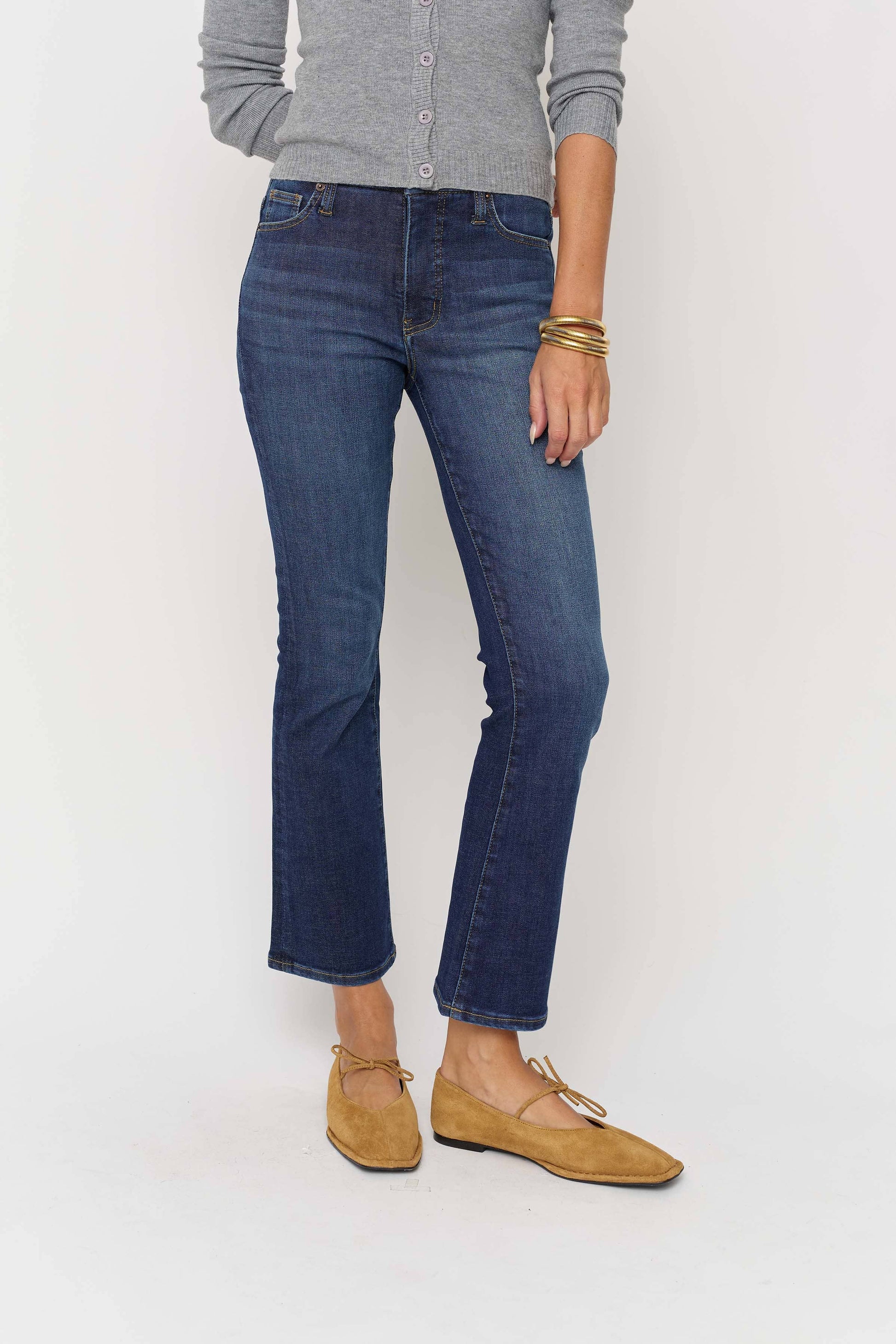 Person wearing blue jeans and a gray sweater on a white background