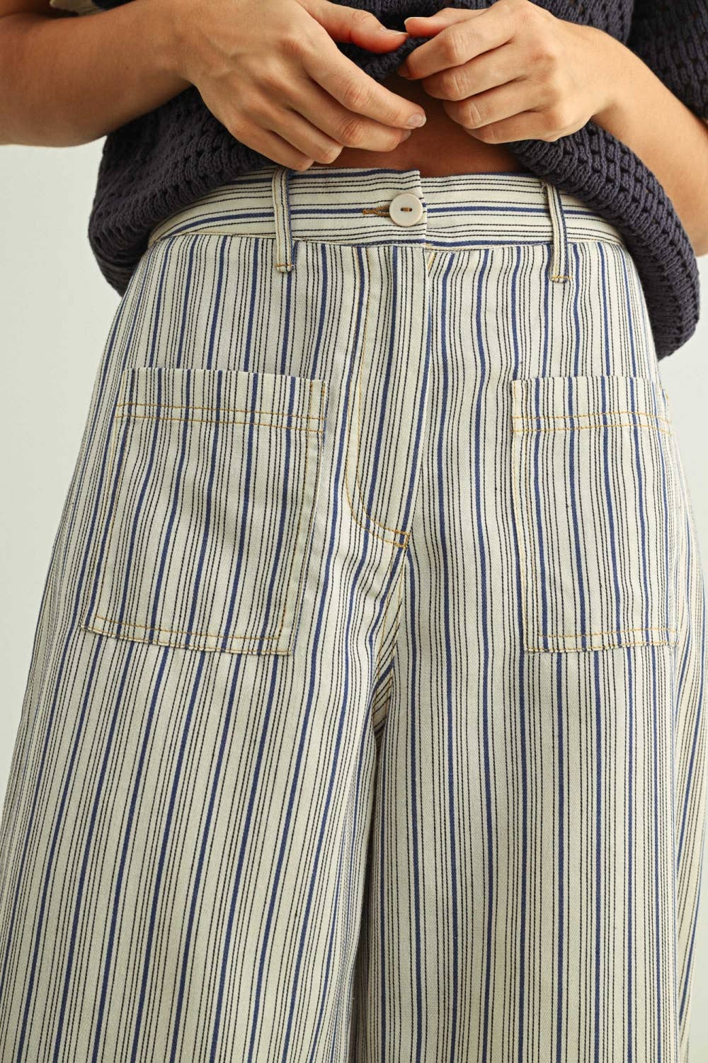 Striped pants with a focus on the waistband and pockets against a neutral background