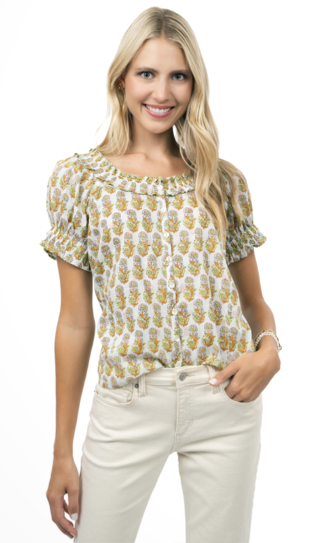 Woman wearing a patterned blouse and white pants on a white background