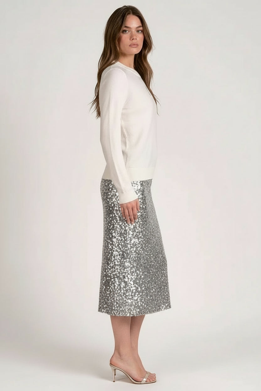 Woman wearing a white sweater with silver sequined midi skirt