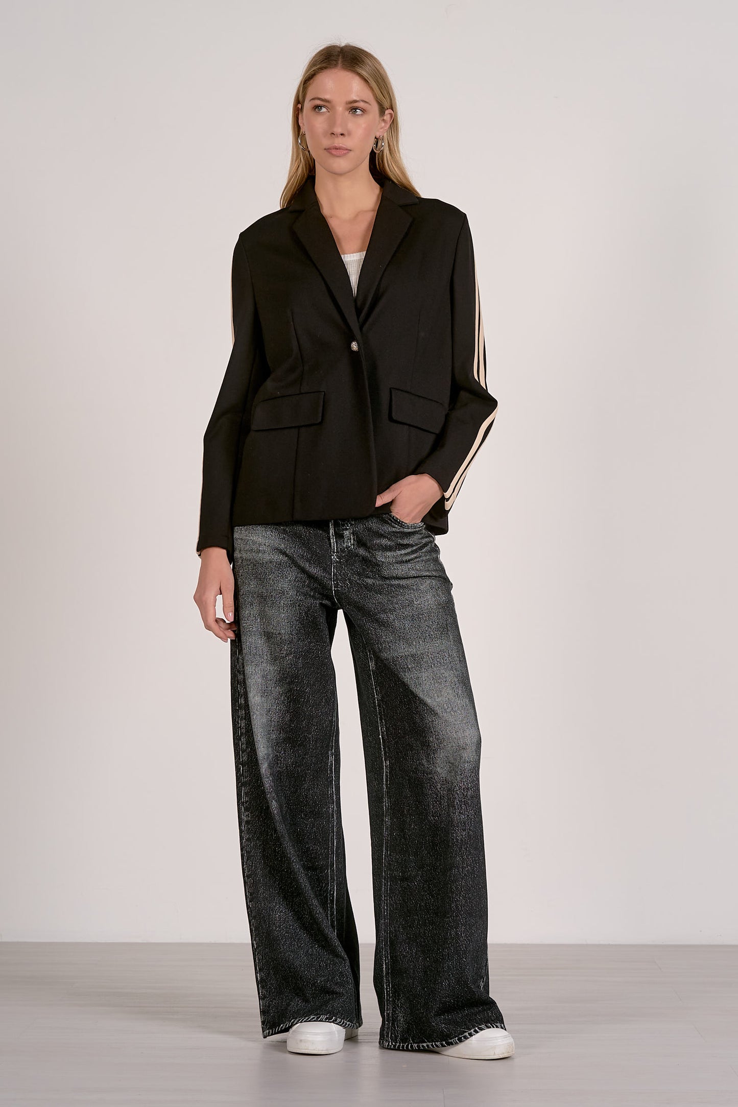 Woman wearing a black blazer and gray jeans on a white background