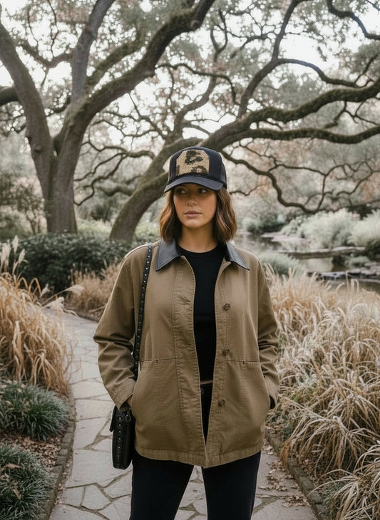 woman wearing a black trucker cap with an animal print kilim patch walking outdoors.
