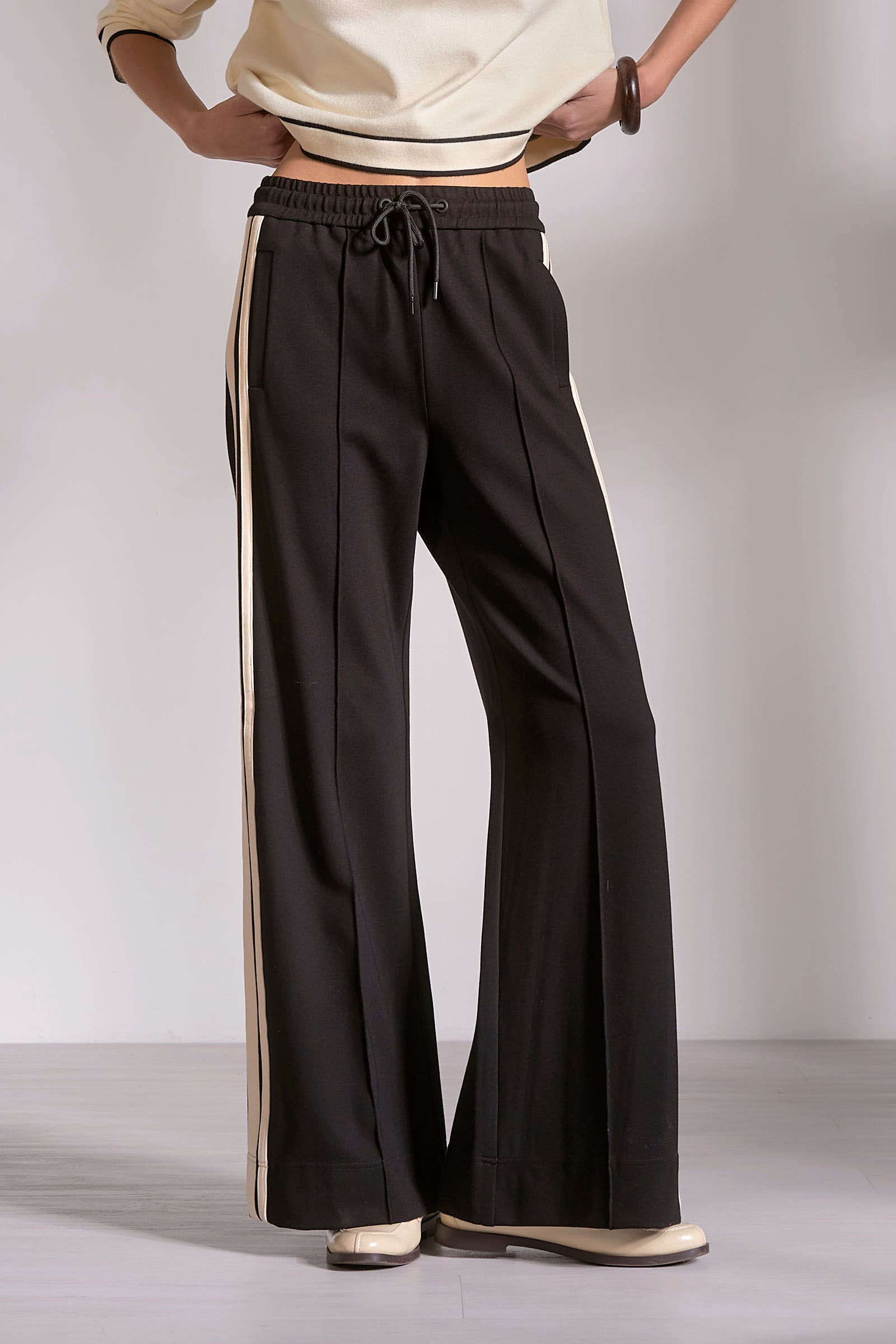Black wide-leg pants with a white stripe on a plain background