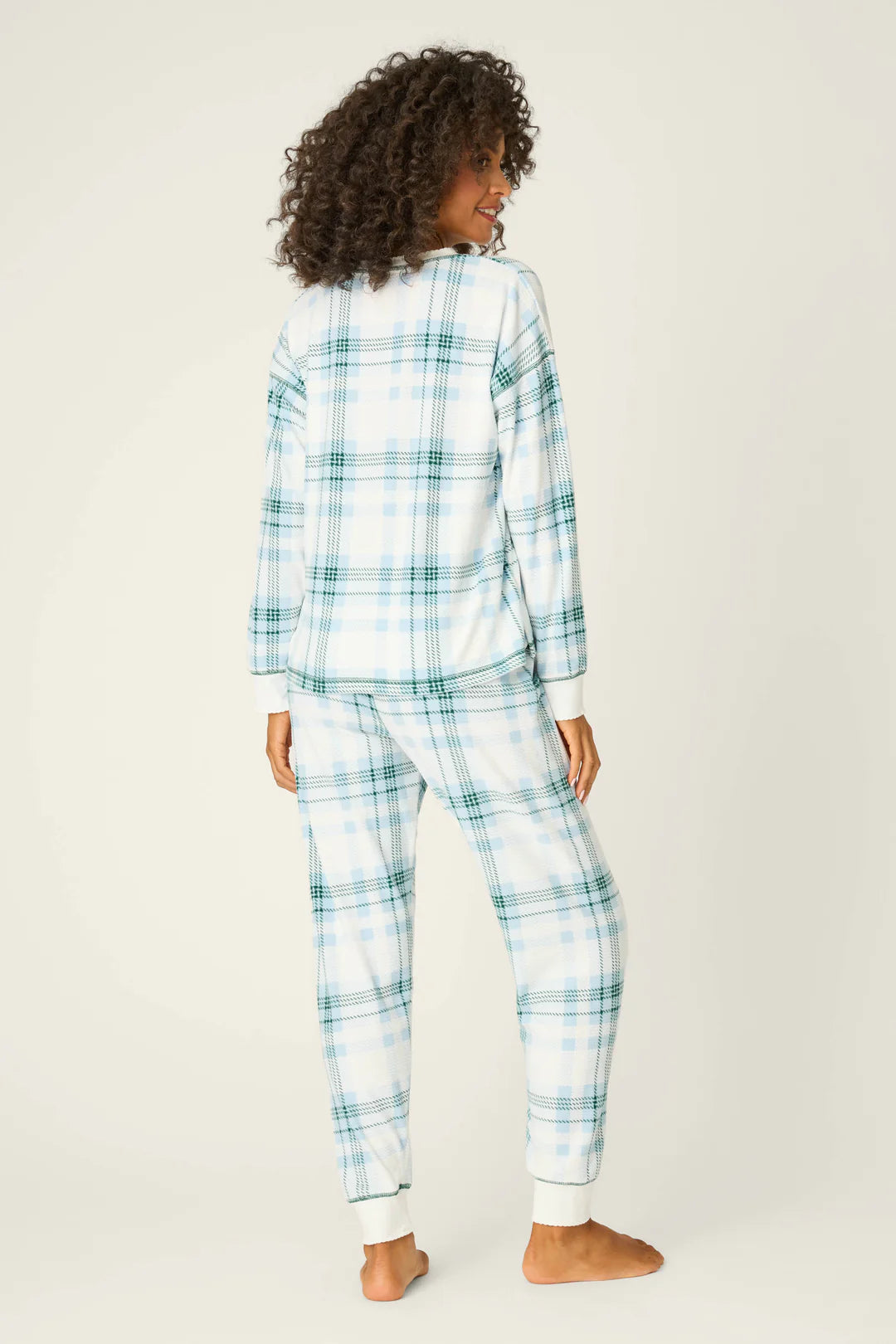 Person wearing a blue and white plaid pajama set on a plain background