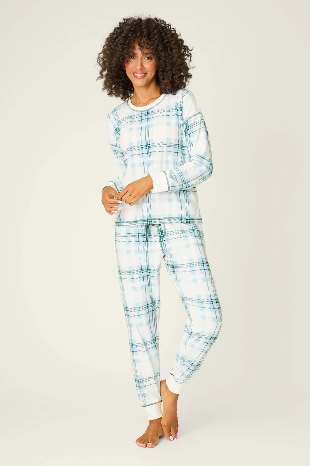 Woman wearing a blue and white plaid pajama set on a plain background
