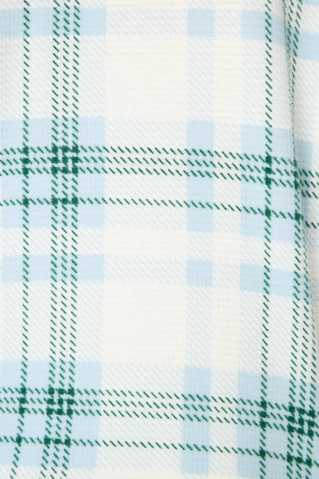 Close-up of a plaid fabric with green and blue patterns on a white background