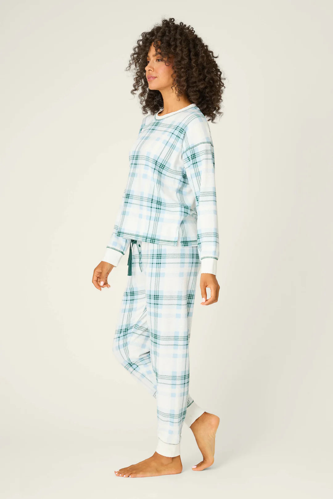 Woman wearing a blue plaid pajama set on a white background