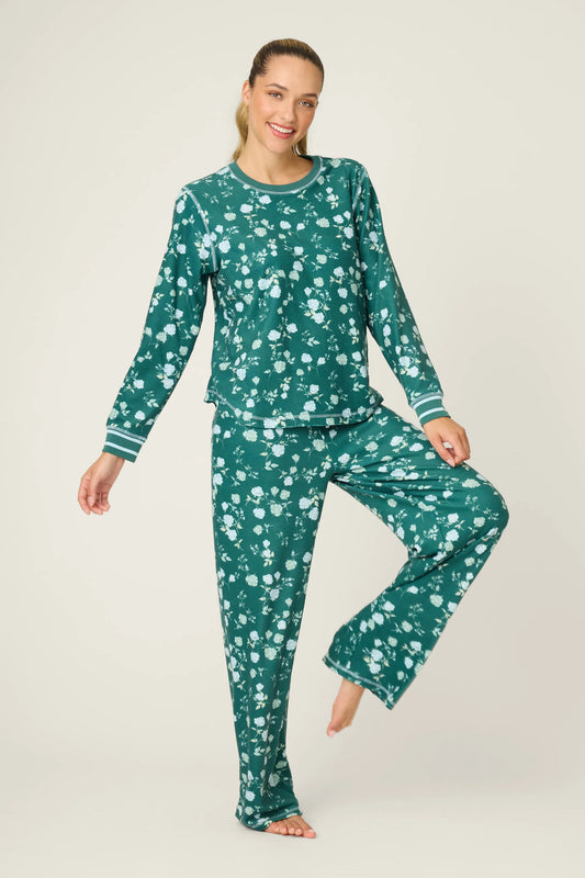 Woman wearing a green floral pajama set on a plain background