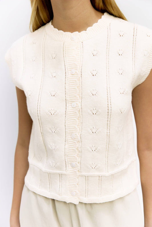 White sleeveless top with intricate detailing on a plain background