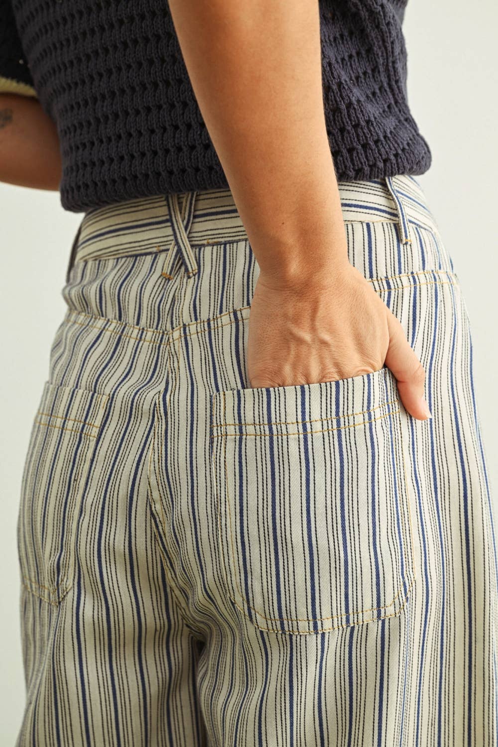 Person wearing striped pants with a neutral background