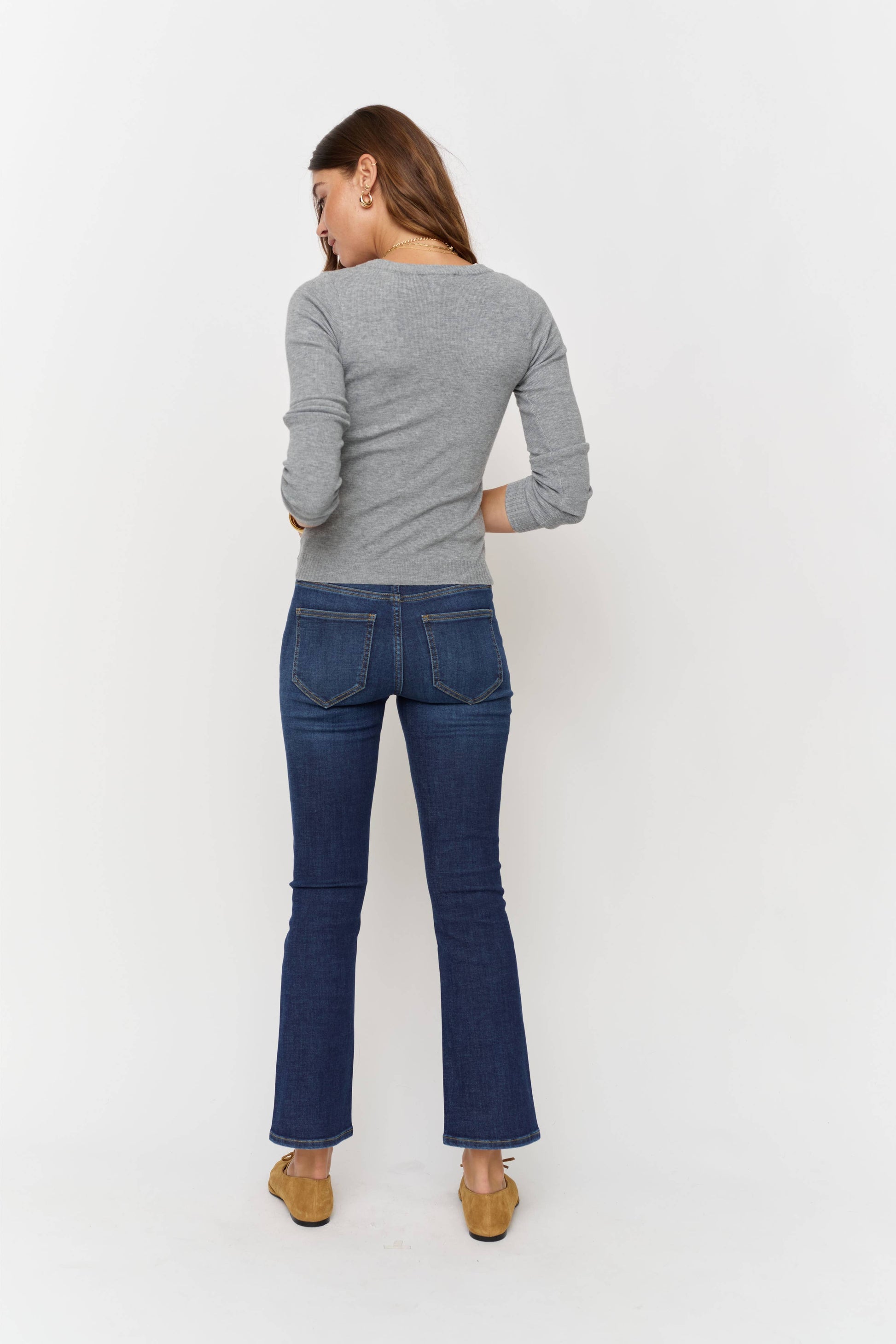 Woman wearing a gray sweater and blue jeans on a white background