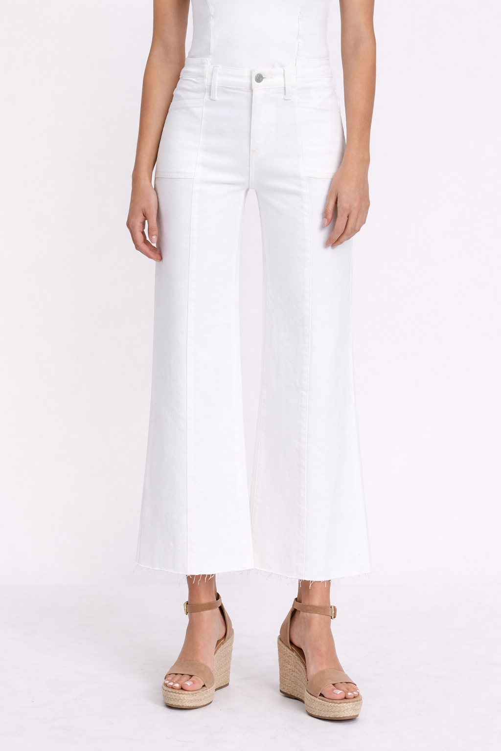 Person wearing white wide-leg jeans and beige sandals on a white background