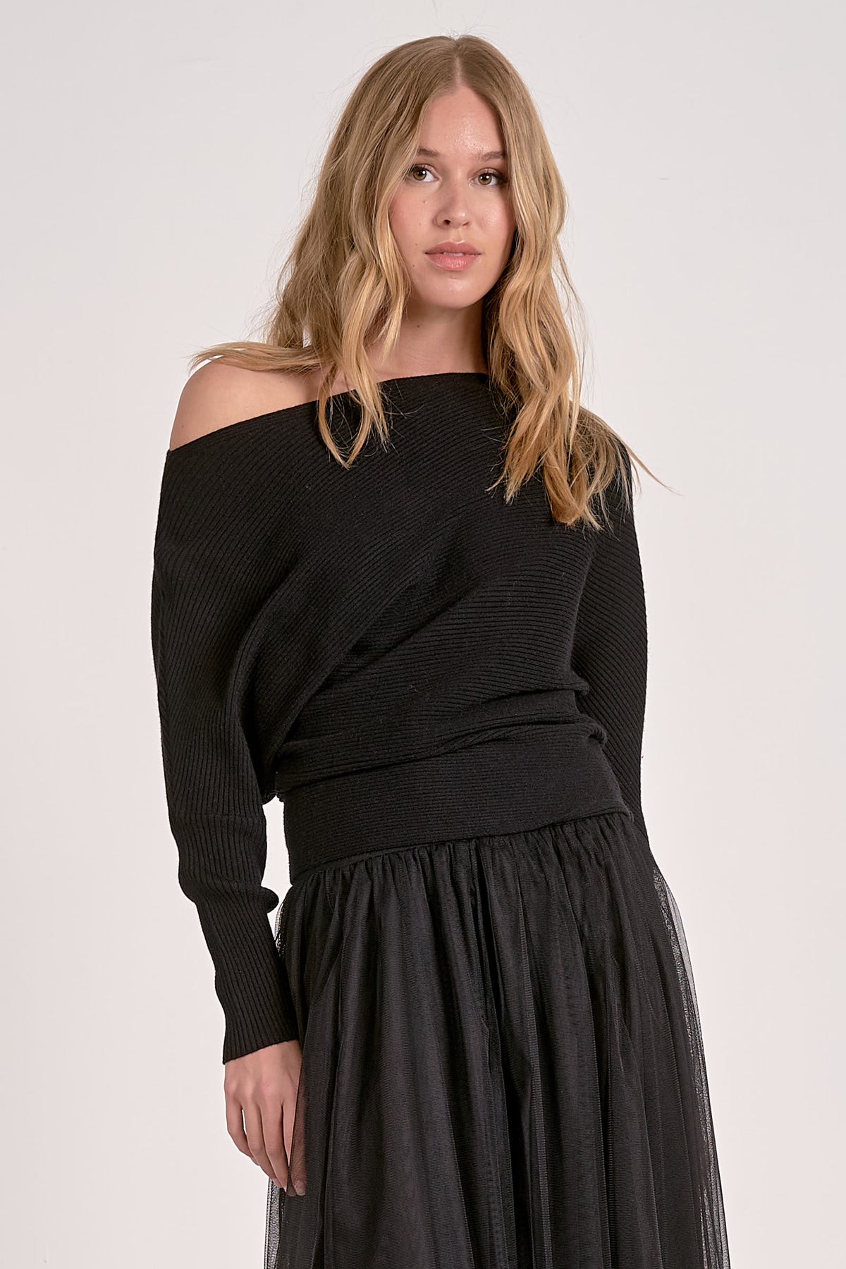 Woman wearing a black off-shoulder top and skirt on a white background