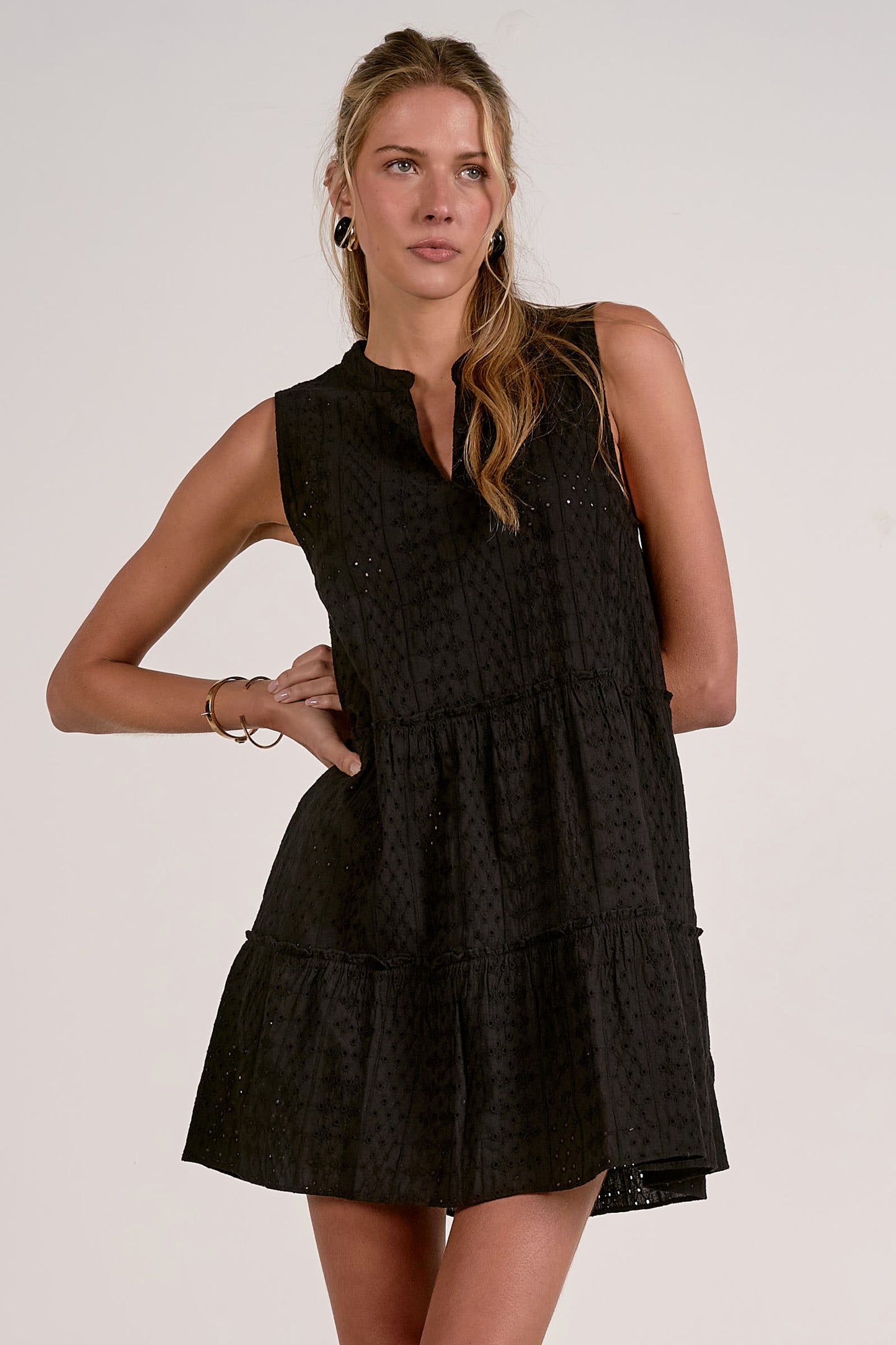 Woman wearing a black sleeveless dress against a plain background