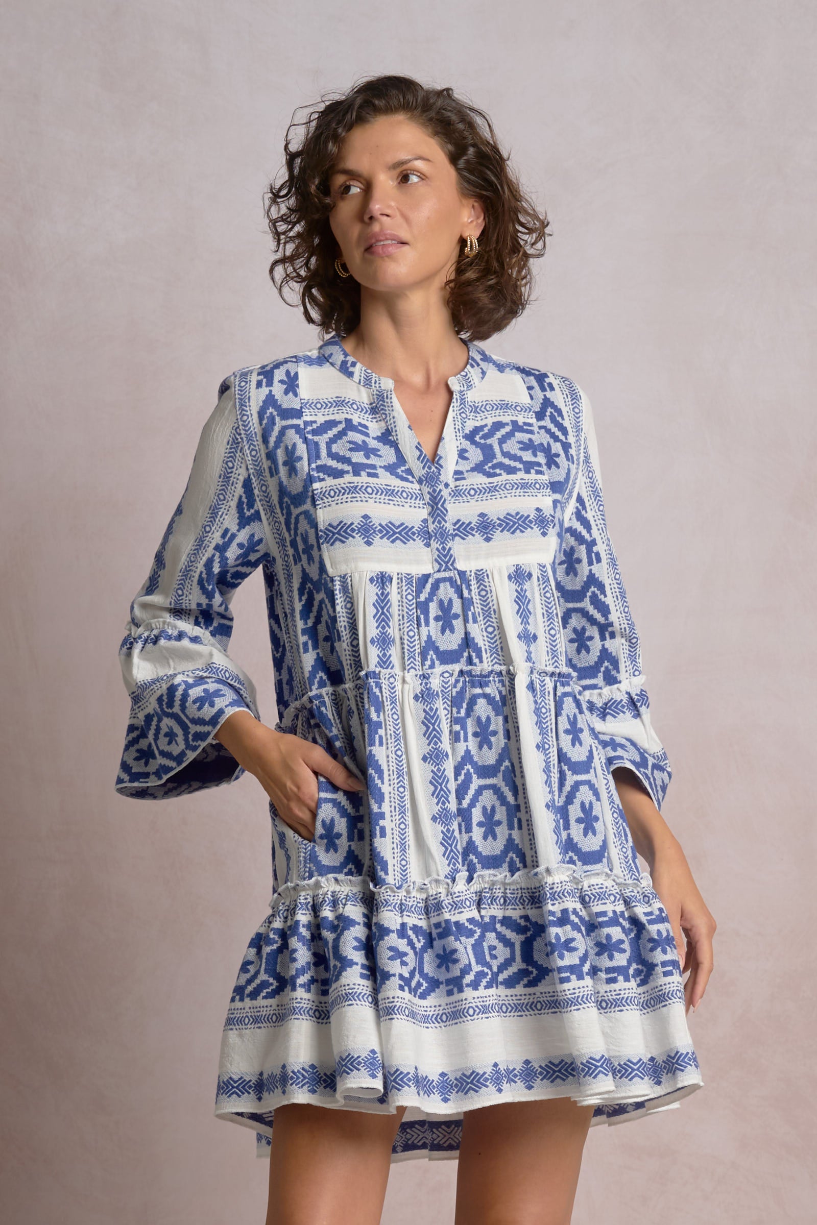 Woman wearing a blue and white patterned dress against a plain background