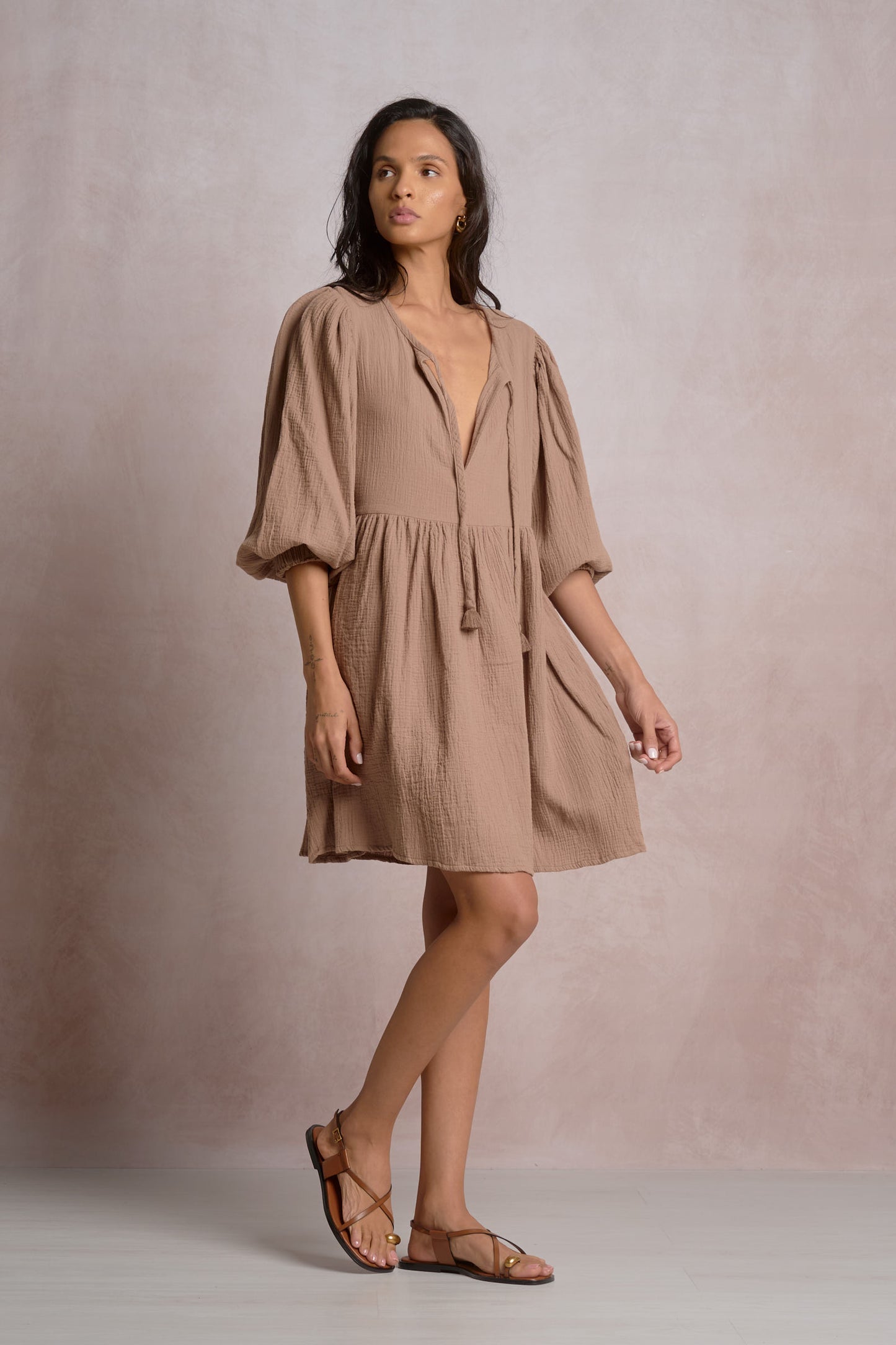 Woman wearing a beige dress against a plain background