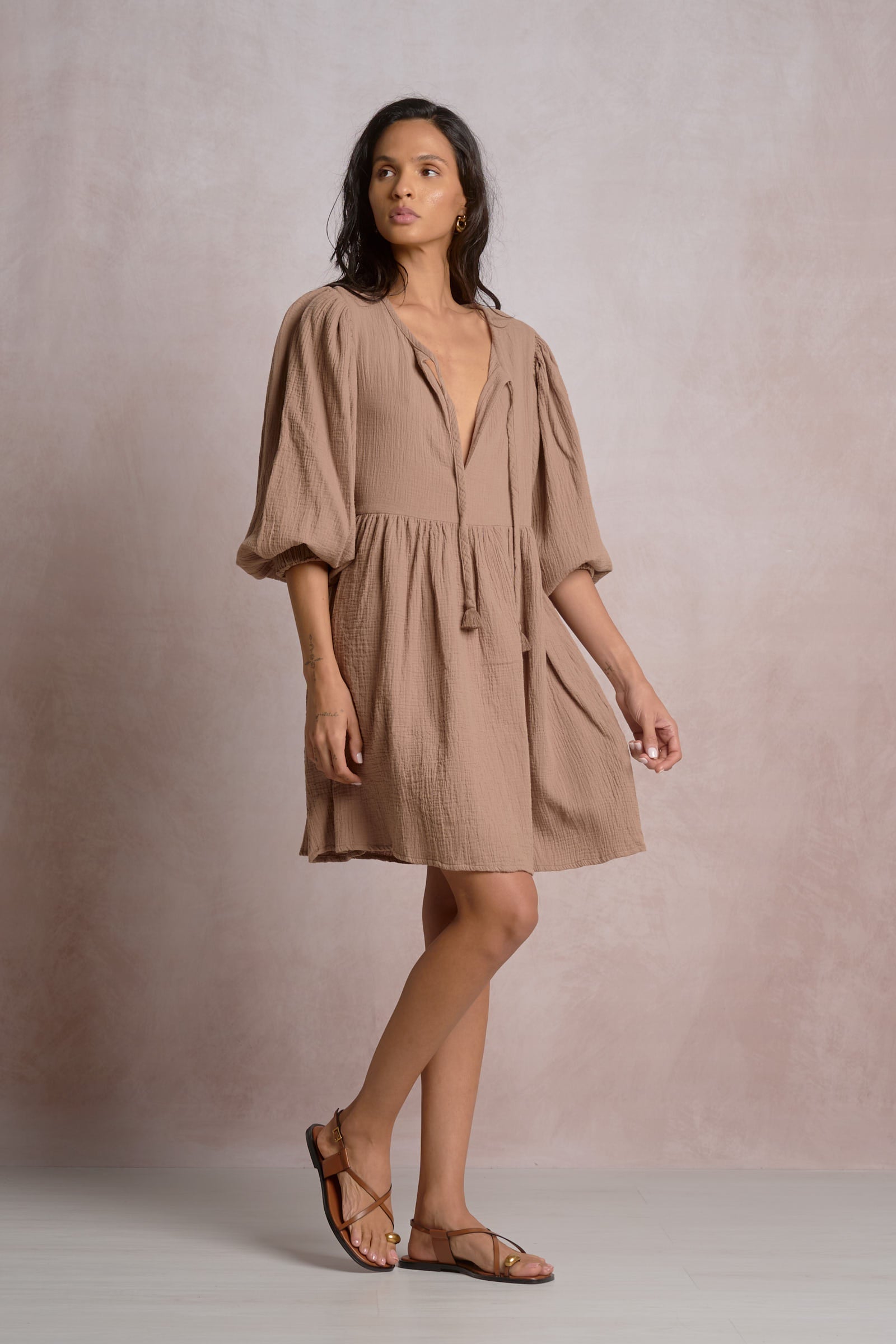 Woman wearing a beige dress against a plain background
