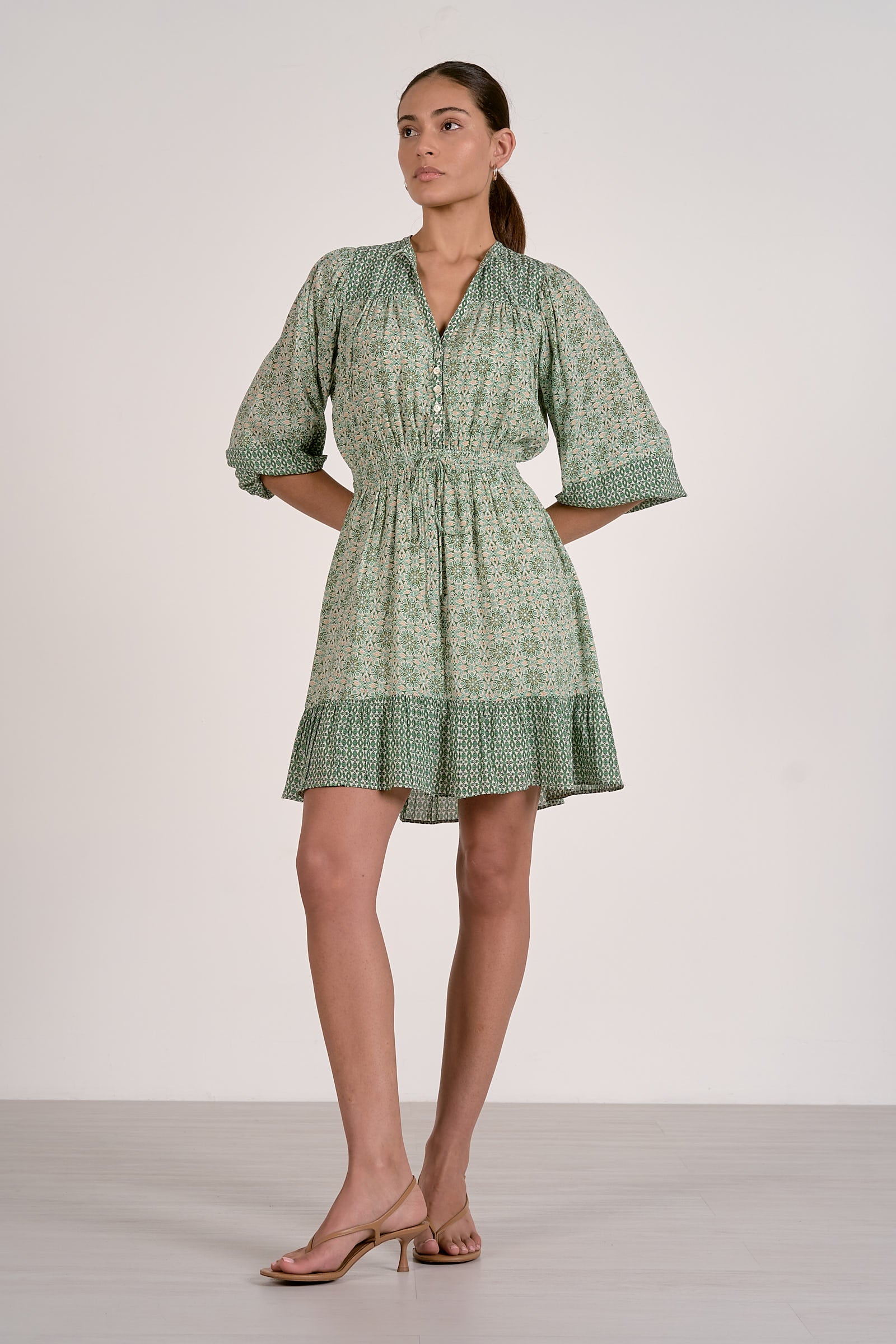Woman wearing a green patterned dress against a white background