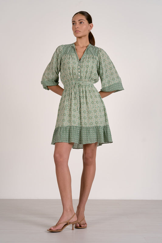 Woman wearing a green patterned dress against a white background
